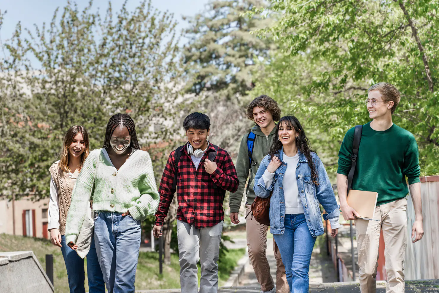 Students laughing as they walk together under spring trees