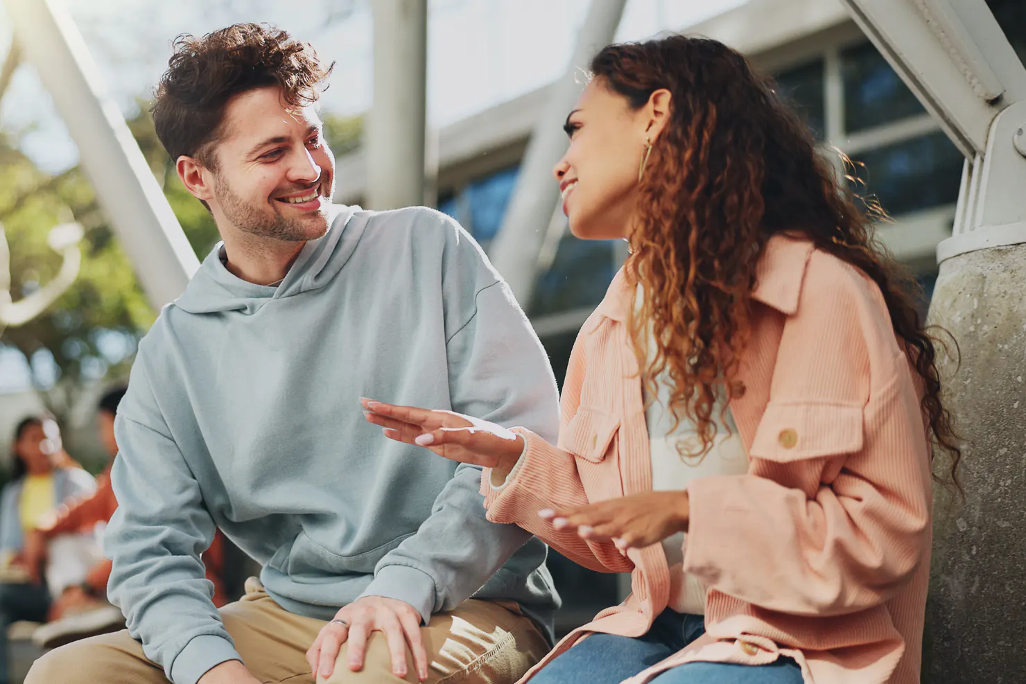 Two friends sitting outdoors, talking and laughing